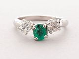a close up view of a three stone emerald and diamond ring