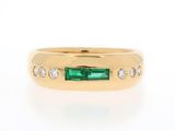 a close up of a gold ring with an emerald stone and diamonds