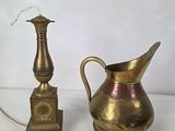 a gold pitcher and a brass candle holder on a white table