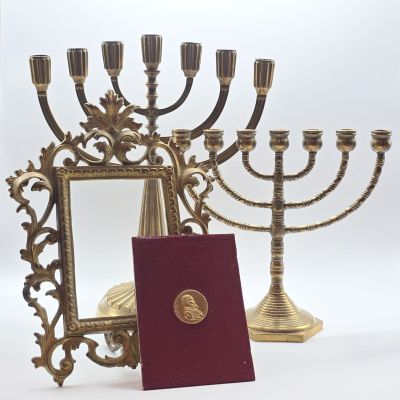 une menorah en or devant laquelle se trouve un livre rouge