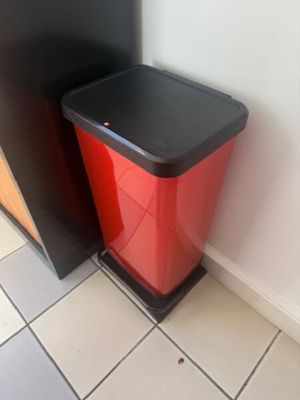a red trash can sitting next to a black trash can