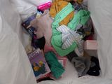 a white bag full of clothes and books on a bed
