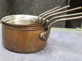three metal pots with spoons in them on a table