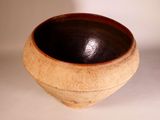 a brown and black bowl sitting on a white surface