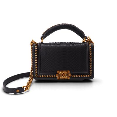 un sac à main noir et doré muni d'une bandoulière en chaîne, sur fond blanc