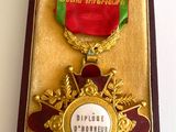 gold medal in a case with a red ribbon and ribbon around it