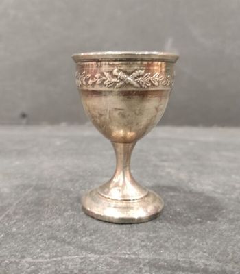 une petite coupe en argent posée sur une table près d'un mur