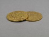 two gold coins sitting on top of each other on a table