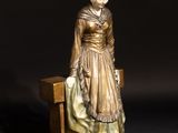 statue of a woman sitting on a bench with a black background