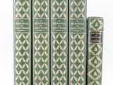 cinq livres verts empilés les uns sur les autres sur une surface blanche