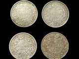 four different types of silver coins on a black background
