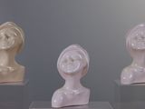 three statues of different shapes on display in a glass case