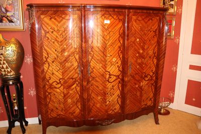 une armoire en bois dans une pièce où est accroché un tableau au mur