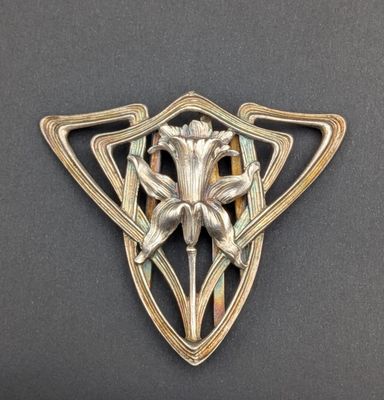 un gros plan d'une broche en métal ornée d'une fleur