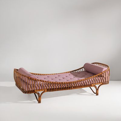 une photo d'une chaise longue en osier avec un coussin rose