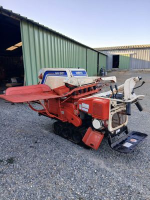 Un tracteur rouge est garé devant un bâtiment.