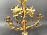 brass candelab with grapes and leaves on it on a grey background