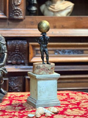 une statue représentant un garçon tenant un ballon, posée sur un socle
