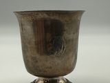 a silver cup sitting on a pedestal on a white surface