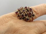 la main d'une femme tenant une bague sertie de grenats