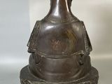 a silver vase with a bird on top of it