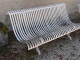 a white metal bench sitting next to a stone wall