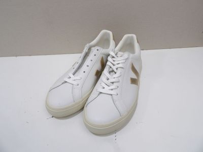 baskets en cuir blanc avec des détails dorés et des lacets sur un fond blanc
