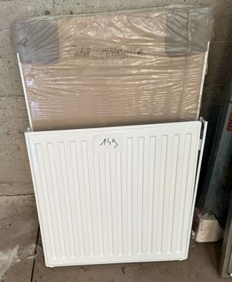 un radiateur blanc posé à côté d'une pile de cartons