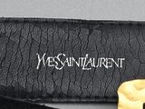 black leather belt with a gold buckle on a grey surface