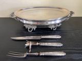 un plateau en argent avec un couteau, une fourchette et un porte-couteau posés sur une table