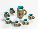 five cups and a mug sitting on a white surface