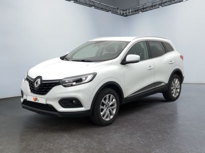 Une voiture blanche est garée dans une pièce blanche au sol noir.