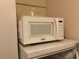 un micro-ondes posé sur une petite table blanche