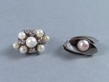 une paire de boucles d'oreilles en perles et diamants posées sur un fond gris