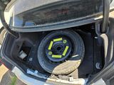 a tire in the trunk of a car with a yellow sticker on it