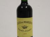 a bottle of red wine sitting on top of a white table