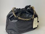 a black purse with a gold chain and a tag on it