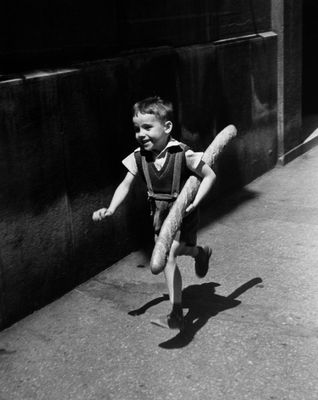 Photographie en noir et blanc d'un jeune garçon tenant une batte de baseball sur un trottoir