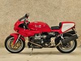 a red motorcycle that is parked in front of a wall
