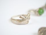a ring with a green stone and a silver ring with a green stone on it