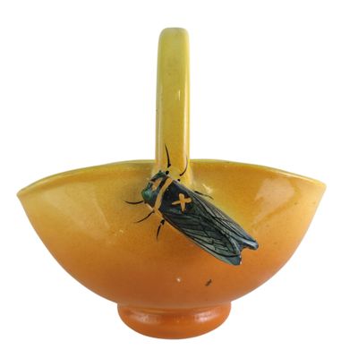 a yellow bowl with a bug on it and a black bug in it