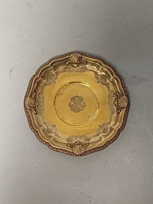 a gold plate on a white table with a white wall behind it