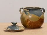 a brown and blue vase with a lid sitting on a table