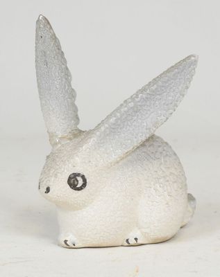 a small white rabbit figurine sitting on a white surface