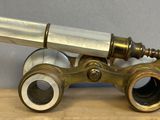 an antique brass telescope on a wooden table with a gray background