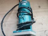 une perceuse électrique posée sur un parquet, avec son cordon d'alimentation