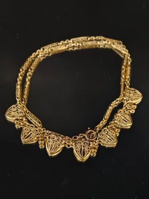 gros plan d'un collier en or sur une surface noire