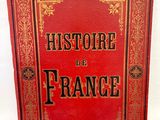 un livre rouge avec des inscriptions noires, posé sur une surface blanche