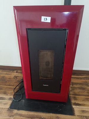 a picture of a red stove in the corner of a room