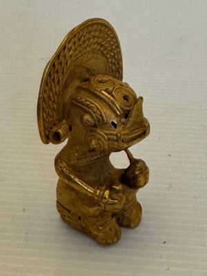 une figurine en or posée sur une surface blanche